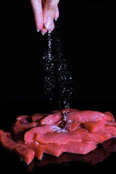 Salt the cut pieces of meat. Cooking at home, in the restaurant. Recipe, menu, chef. Ingredients for cooking