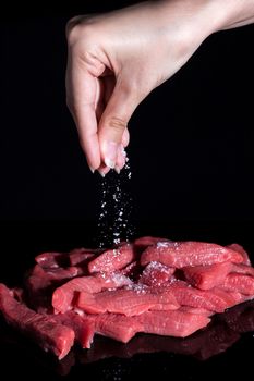 Salt the cut pieces of meat. Cooking at home, in the restaurant. Recipe, menu, chef. Ingredients for cooking