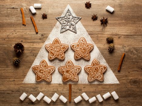Christmas cookies and cookie cutters on wooden background. Christmas composition. Winter, new year concept. Flat lay, top view. Cones, cinnamon, coriander and marshmallow. 2020