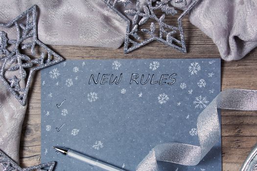 Words and patterns on gray paper. New year, new rules. Motivation, plan, schedule, task, new life. Christmas, holiday. Snowflakes and Christmas toys. The silver background.