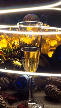 A glass of champagne on the Christmas decorations. happy New Year. Christmas composition. 2020. Christmas toys and lights garlands. Restaurant, bar party, light show.