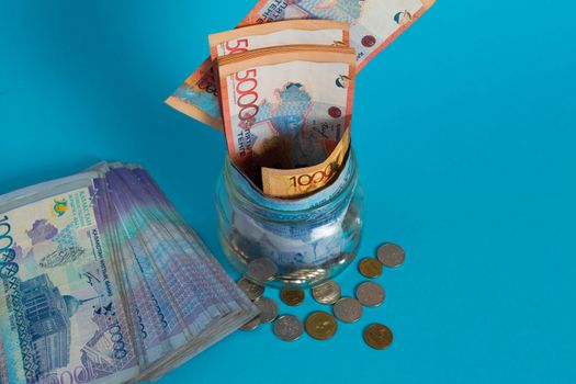 Tenge in a glass jar. Kazakhstan, KZ, KZT. Banknote, paper currency, coins, Bank. Salary, credit, savings, pay and spend. Business and Economics.
