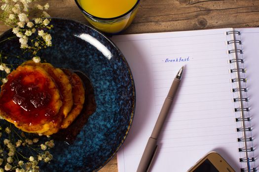 Beautiful Breakfast. Pancakes with jam and orange juice. Flowers and stylish dishes. Daily planner with the inscription Breakfast. A healthy life style. Flat lay. Luxury decor.