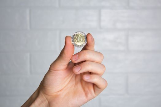 Hold the tenge coin in your hand. Close up. New Kazakhstan coin 200 tenge. Money, Bank, save, spend.