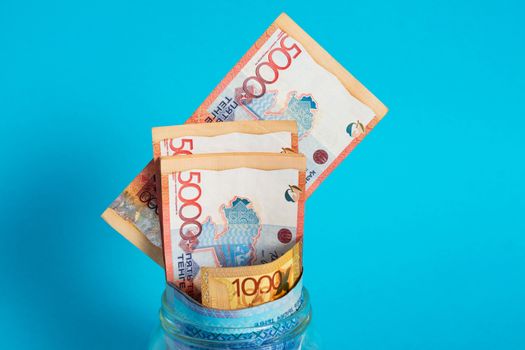 Tenge in a glass jar. Kazakhstan, KZ, KZT. Banknote, paper currency, coins, Bank. Salary, credit, savings, pay and spend. Business and Economics.
