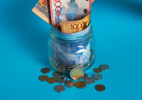 Tenge in a glass jar. Kazakhstan, KZ, KZT. Banknote, paper currency, coins, Bank. Salary, credit, savings, pay and spend. Business and Economics.