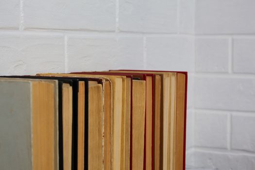 A stack of old books. Bookstore, library, bookshelf. Vintage, retro, antique.  Study, education, school, University. Literature, history, science. Books against a white brick wall.