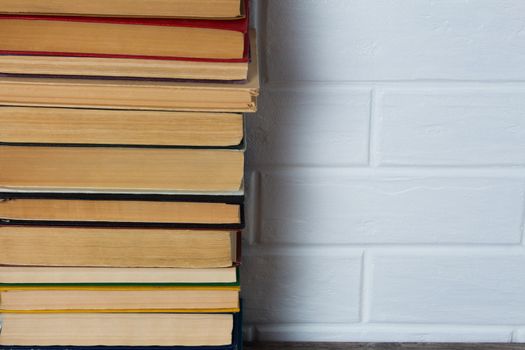 A stack of old books. Bookstore, library, bookshelf. Vintage, retro, antique.  Study, education, school, University. Literature, history, science. Books against a white brick wall. copy space