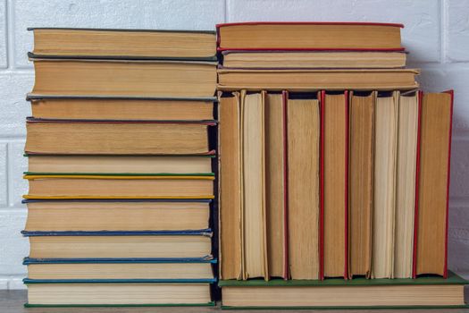 A stack of old books. Bookstore, library, bookshelf. Vintage, retro, antique.  Study, education, school, University. Literature, history, science. Books against a white brick wall.