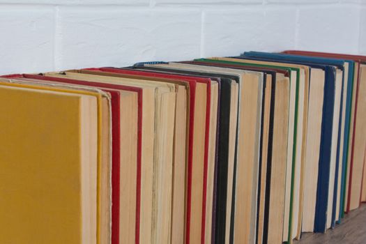 A stack of old books. Bookstore, library, bookshelf. Vintage, retro, antique. Study, education, school, University. Literature, history, science. Books against a white brick wall.