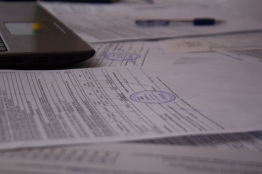 Office Desk with papers, receipts and documents. Work with documents at the plant or enterprise. Laptop or computer on the office Desk with documents. Job.