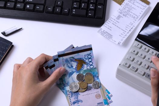 Tenge at the cashier accountant in the hands of the workplace in the office. The cashier counts the money KZT in the workplace in Kazakhstan.