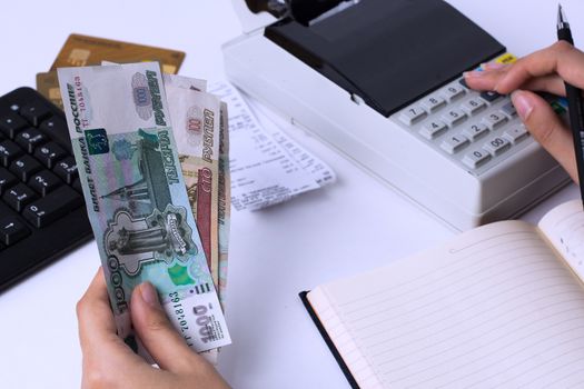 The issue of wages in Russia. Accountant cashier counts the money in rubles and fills the reports and statements. Office worker in the workplace.