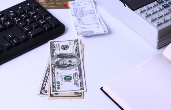 Dollars lie on the desktop in the office or Bank next to the cash register, keyboard, notebook and check. Workplace Manager cashier and issuing wage workers.