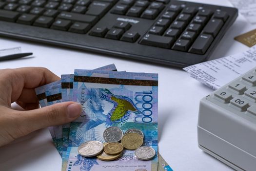 Tenge at the cashier accountant in the hands of the workplace in the office. The cashier counts the money KZT in the workplace in Kazakhstan. Salary in Kazakhstan