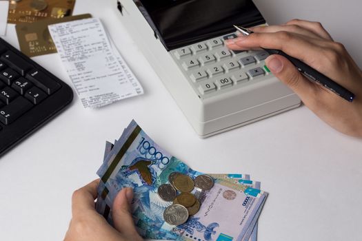 Tenge at the cashier accountant in the hands of the workplace in the office. The cashier counts the money KZT in the workplace in Kazakhstan. Salary in Kazakhstan