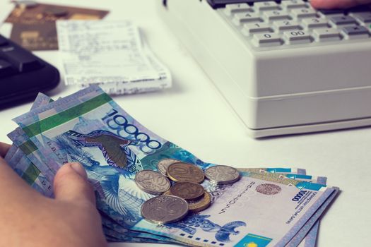 Tenge at the cashier accountant in the hands of the workplace in the office. The cashier counts the money KZT in the workplace in Kazakhstan. Salary in Kazakhstan