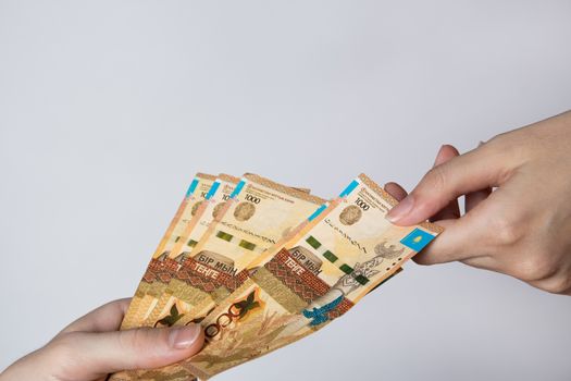 Paper banknotes tenge KZT people hold in their hands on white background. Tenge is the national currency of Kazakhstan.