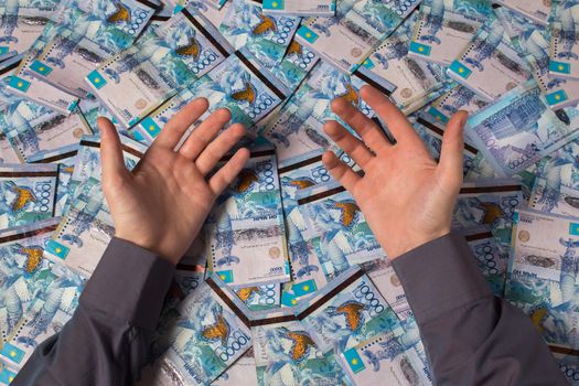 Hands are on a table full of Kazakhstan tenge money. Paper banknotes tenge KZT. Tenge is the national currency of Kazakhstan. bank of Kazakhstan