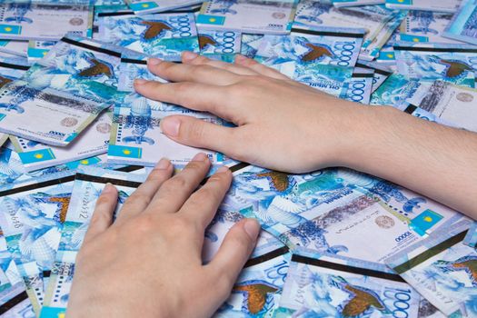 Hands are on a table full of Kazakhstan tenge money. Paper banknotes tenge KZT. Tenge is the national currency of Kazakhstan. bank of Kazakhstan