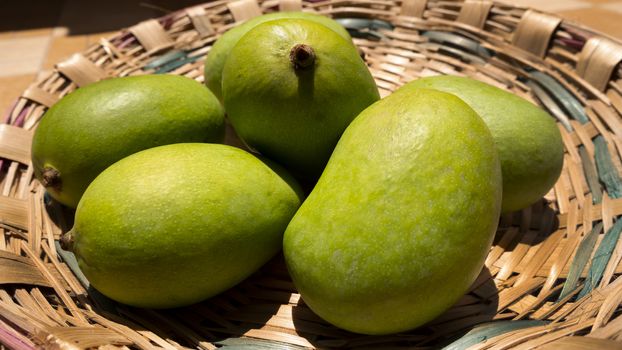 a close up view of green mangoes on bamboo basket