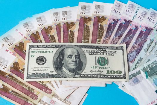 Paper banknotes of Russian rubles and the us dollar.100 Dollars on Russian rubles. Rubles are the national currency of Russia. bank of Russia.Russian ruble on a blue background.The growth of the ruble