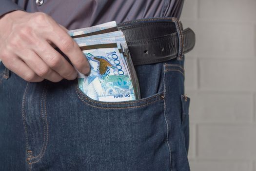 The guy pulls the tenge money out of his jeans. Tenge KZT on white background. Banknotes tenge. Money Kazakhstan Tenge