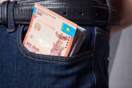 The guy takes the Tenge money Out of his jeans pocket. Paper banknotes tenge KZT. Tenge is the national currency of Kazakhstan. bank of Kazakhstan