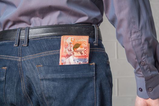 The guy pulls the tenge money out of his jeans. Tenge KZT on white background. Banknotes tenge. Money Kazakhstan Tenge