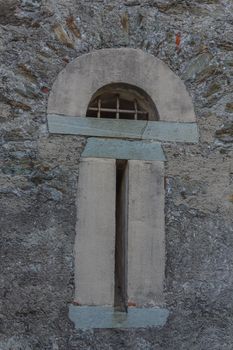 detail of a slit with a wrought -iron arch  grating of an ancient castle