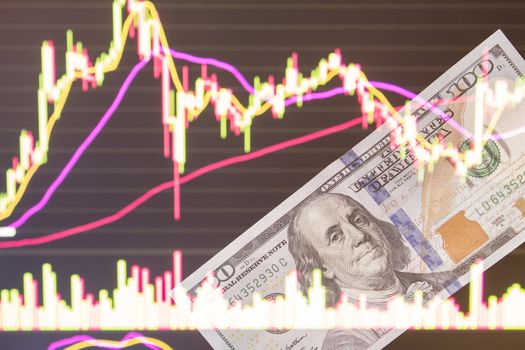 dollars in front of a laptop monitor with a price chart.Forex and trading.A trader trades stocks,bonds and securities or currencies on the Forex market or stock exchange for us dollars.100 dollars.