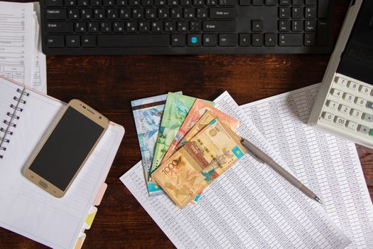 Tenge of KZT are on the table next to the computer, Notepad, telephone and documents. Paper banknotes tenge KZT. Bank of Kazakhstan