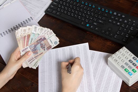 Hands holding Russian rubles at the Desk in the office. Russian Russian cashier Manager at the workplace in a Russian Bank.Issuing salaries, pensions and unemployment benefits in Russia