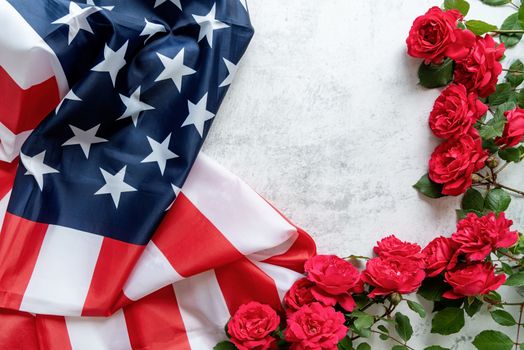 Independence Day USA concept. Memorial Day. Red roses over the USA flag top view flat lay with copy space