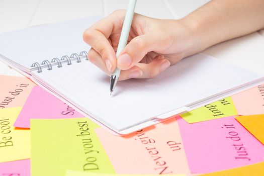 The hand writes on a white page in the daily planner.Student, study, synopsis. Affirmations, visualization, to-do lists. Plan, strategy, dream, desire. Cards with words. Concept, project.
