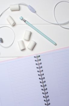Daily planner on a white wooden background. Close-up, copy space, clear space, mockup. Clean sheet, flat lay, top view. Notepad, pen, headphones, to-do list, marshmallow