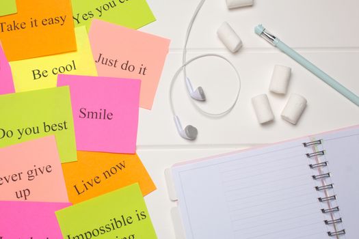 Daily planner, pen, headphones, and colorful word cards. Close-up on a white background. Copy space. Clean sheet, flat lay, top view.  To-do list, marshmallow. Color sheets with quotes. Visualization 