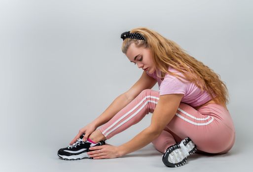 Fitness, sport, training and lifestyle concept. Athletic acrobat woman wearing pink sportswear stretching in the studio isolated on gray background