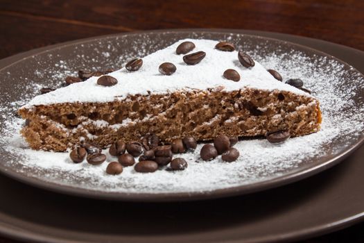 A piece of chocolate cake with sugar and coffee beans. Food, dessert, sweet. Biscuit, brownie, tiramisu, cheesecake. Cook at home. Bakery products.