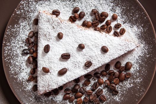 A piece of chocolate cake with sugar and coffee beans. Food, dessert, sweet. Biscuit, brownie, tiramisu, cheesecake. Cook at home. Bakery products.