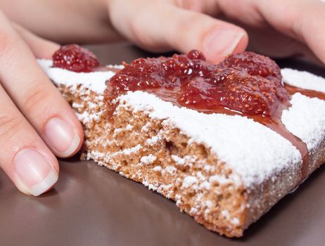 Hands  with a piece of cake with strawberry jam and sugar. Dessert, food, sweet, baking. Biscuit, brownie, tiramisu, cheesecake. Cook at home, homemade, closeup, Bakery products.