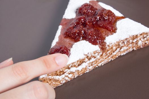 Hand holding a piece of cake with strawberry jam and sugar. Dessert, food, sweet, baking. Biscuit, brownie, tiramisu, cheesecake. Cook at home, homemade, closeup, Bakery products.