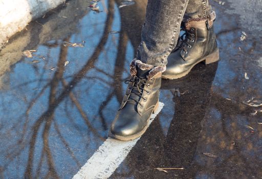 Women's feet in a puddle. Shoes, boots, go, walk. Asphalt, markings, dirt. Autumn, slush, spring. Close up. Casual