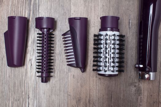 Set of hair dryer attachments on a wooden background. Curling iron, hair straightener. Hot styling, boar bristles, hair care. Beauty salon, styling, haircut. Beauty, fashion, style.