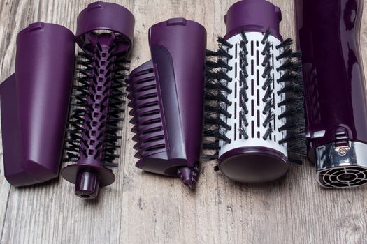 Set of hair dryer attachments on a wooden background. Curling iron, hair straightener. Hot styling, boar bristles, hair care. Beauty salon, styling, haircut. Beauty, fashion, style.