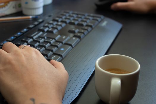 Woman working at home on her computer while drinking an espresso