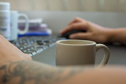 Woman working at home on her computer while drinking an espresso