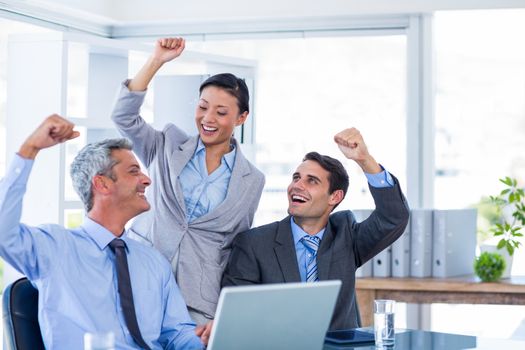 Happy business people cheering together in office