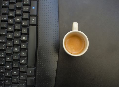Woman working at home on her computer while drinking an espresso