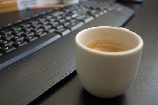 Woman working at home on her computer while drinking an espresso